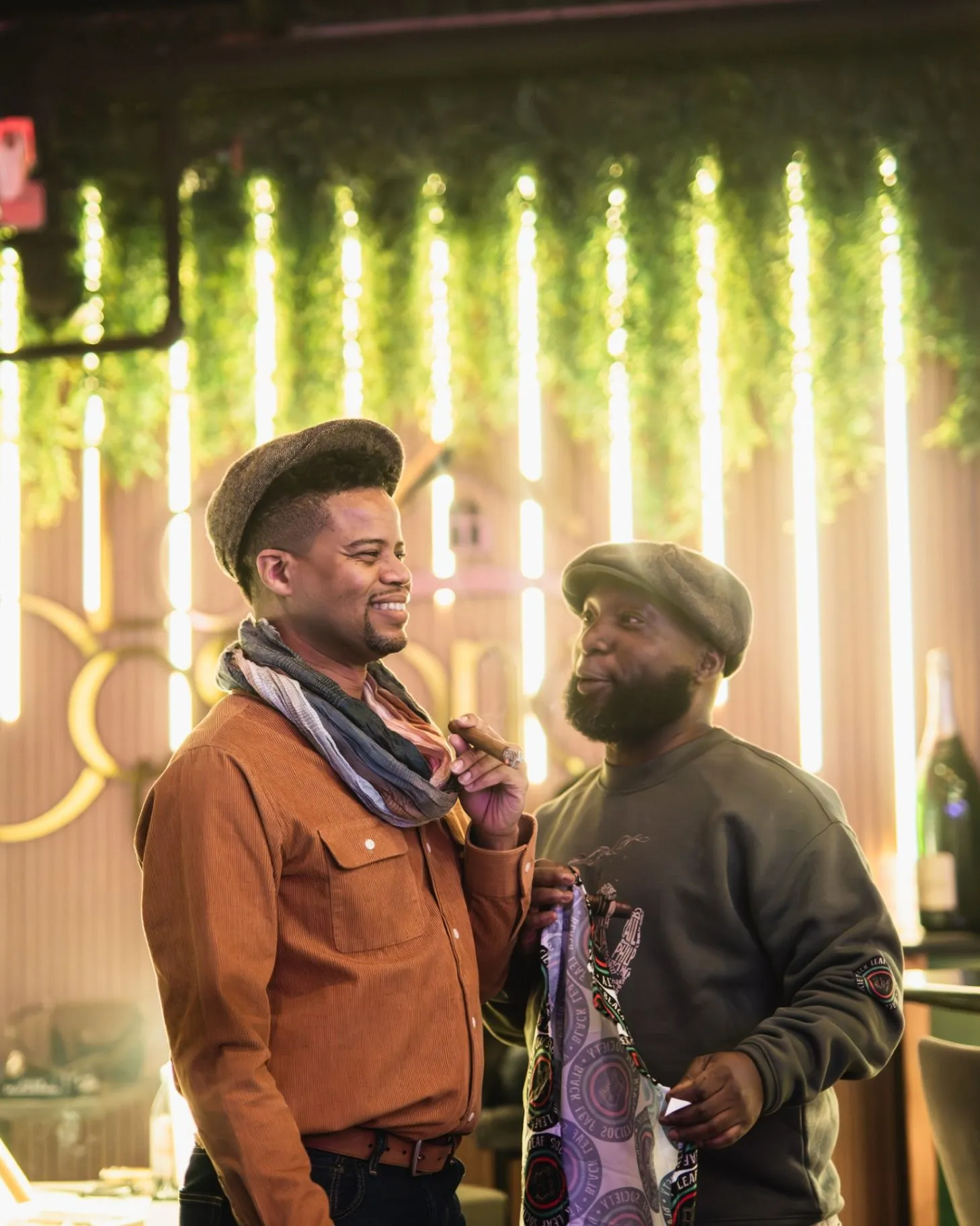 Two Society friends talking with cigars beneath warm hanging lights